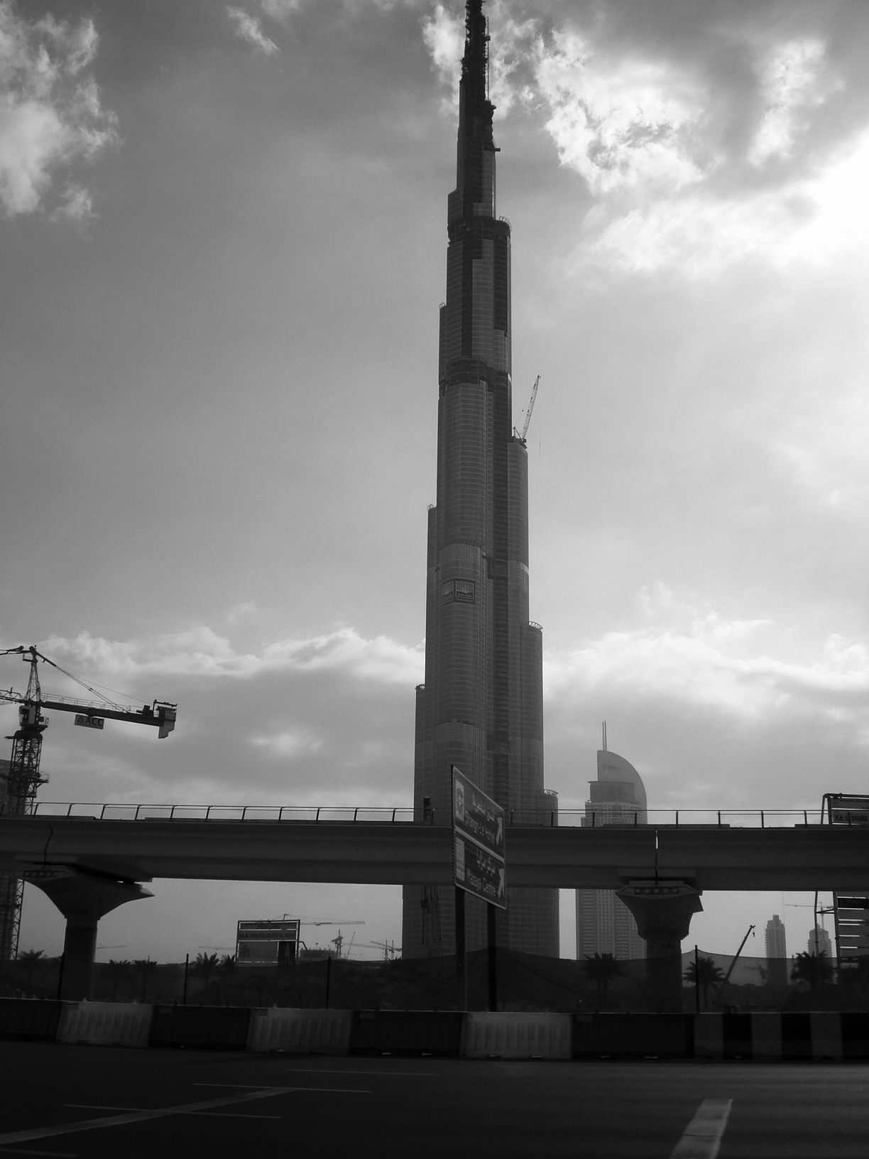 Burj Khalifa under construction behind a metro viaduct